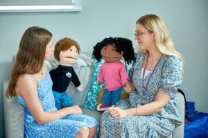 Just 'B' support worker and student talking with puppets